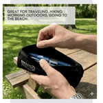 Person holding a black zippered pouch with a blue item inside, outdoors. 